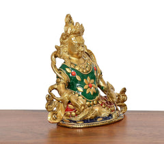 Side view of antique brass Kubera protector statue with green robe and floral inlays