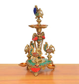 Brass peacock oil lamp stand with green base, red accents, and four side cups