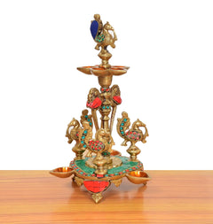Brass peacock oil lamp stand with green base, red accents, and four side cups