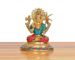 Seated brass goddess figure with tall gold crown, teal torso, red checkered skirt, holding staff.