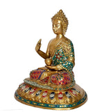 Brass Buddha statue side view, golden face and teal robe holding a small bowl