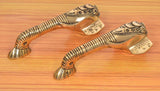 Brass Ganesha door handle pair with ornate detailing, curved handles on display.