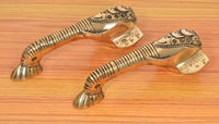 Brass Ganesha door handle pair with ornate detailing, curved handles on display.