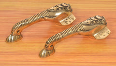 Brass Ganesha door handle pair with ornate detailing, curved handles on display.