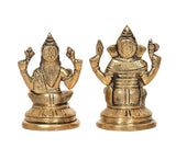 Brass Lakshmi and Ganesha idol pair, close-up angle showing crowns and raised hands.