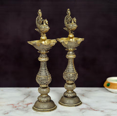Decorative peacock oil lamp pair in bronze, side view of top bowl and stand.