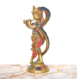 Side view of brass Krishna sculpture with serpent hood, red patterned dhoti and blue drape.
