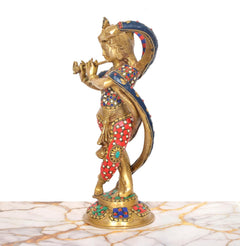 Side view of brass Krishna sculpture with serpent hood, red patterned dhoti and blue drape.