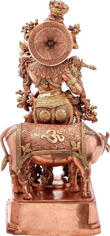 Krishna on cow statue, copper-toned brass, rear view with circular halo detail