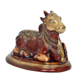 Seated Nandi bull statue, gold-toned head, red body, patterned saddle and base