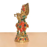Side view of Krishna brass idol with multicolor halo and patterned red-green attire