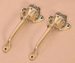 Golden brass Ganesha face door handles, angled view showing curved levers