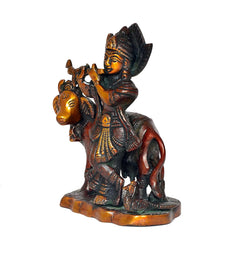 Side view of Krishna flute statue riding cow, ornate jewelry details