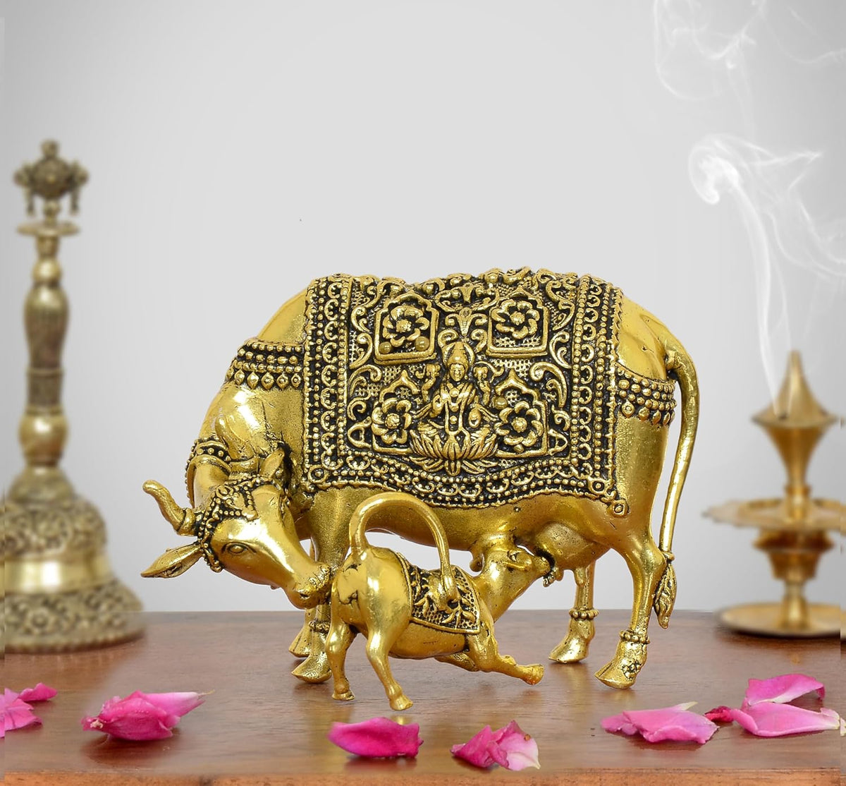 Golden brass cow figurine with calf, ornate engraved detailing, raised legs