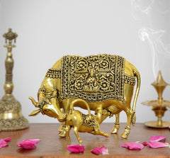 Golden brass cow figurine with calf, ornate engraved detailing, raised legs