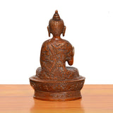 Brass Buddha idol rear view with carved robe pattern, ornate base
