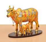 Golden-look Kamdhenu cow statue with calf, ornate jewelry chain and bell detail.