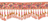 Close-up: pink decorative toran strip with gold and orange bell-like tassels
