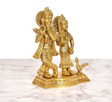 Gold-tone brass Radha Krishna idol with peacock, detailed clothing and crowns.
