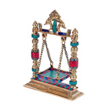 Gold brass Krishna jhula idol, side view with chain swing and turquoise/red tiled base