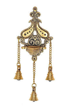 Brass wall diya with ornate peacock-like frame and three bells on chains