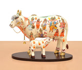 Two-piece resin cow and calf statue on a round base, white with colorful character artwork