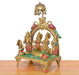 Brass Ram Darbar murti side view, ornate sun-peacock chhatra over singhasan