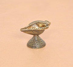 Brass conch oil diya lamp from front side, textured pedestal base and engraved shell rim