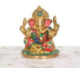 Gold brass Ganesha murti with red, teal and green gemstone-style accents and ornate base