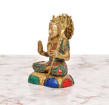 Brass Shiva statue from side view, seated pose with raised hand and trident