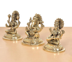 Brass Lakshmi Ganesha Saraswati idols, angled view of three seated gods, gold-tone