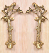 Set of 2 brass parrot tree door handles on a light wood panel, oval screw plates