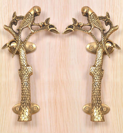 Set of 2 brass parrot tree door handles on a light wood panel, oval screw plates