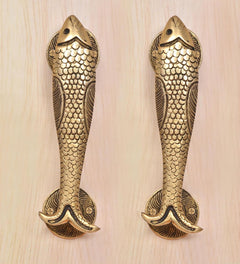 Two fish-shaped brass door handles with scale texture and curved tail ends.