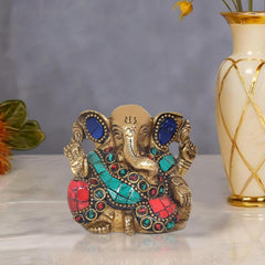 Brass Ganesha idol with blue gemstone eyes, turquoise and red jeweled detailing, seated