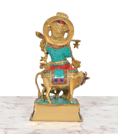 Rear view of brass Krishna flute idol riding cow, multicolor inlay on clothing