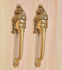 Close-up of golden brass long-neck door handles with detailed face head designs