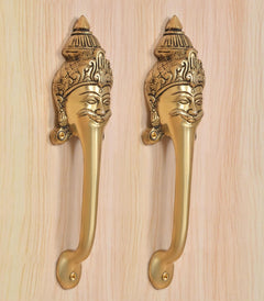 Close-up of golden brass long-neck door handles with detailed face head designs