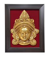 Close view of brass Maa Durga face idol relief in wooden frame with red backing