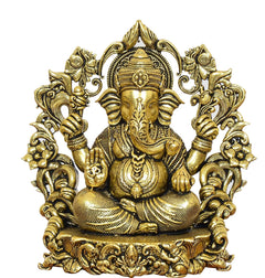 Golden brass Ganesha idol close-up, four arms raised, ornate floral arch