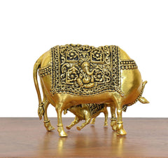 Golden brass cow figurine with calf, side detailing with etched ornaments and tail