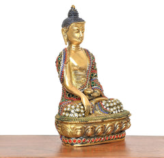 Meditating Buddha idol, brass tone, side view with multicolor jeweled robe details