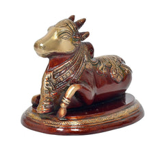 Close view Nandi bull statue, gold-toned face and ornate collar on red body