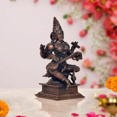 Maa Saraswati seated statue showing veena and multi-armed pose, dark bronze