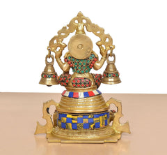 Brass Lakshmi statue rear view with arched crown frame, bells, and multicolored jewelry
