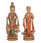 Two resin swami statues standing front view, detailed crowns, robes, jewelry, floral base