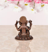 Copper Ganesha idol rear view with large crown and four arms, seated on lotus base