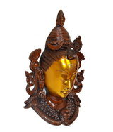 Shiva mask idol angled view, golden closed-eye face with ornate dark surround