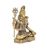 Brass Lord Shiva statue in side view, seated with trident staff and small drum.