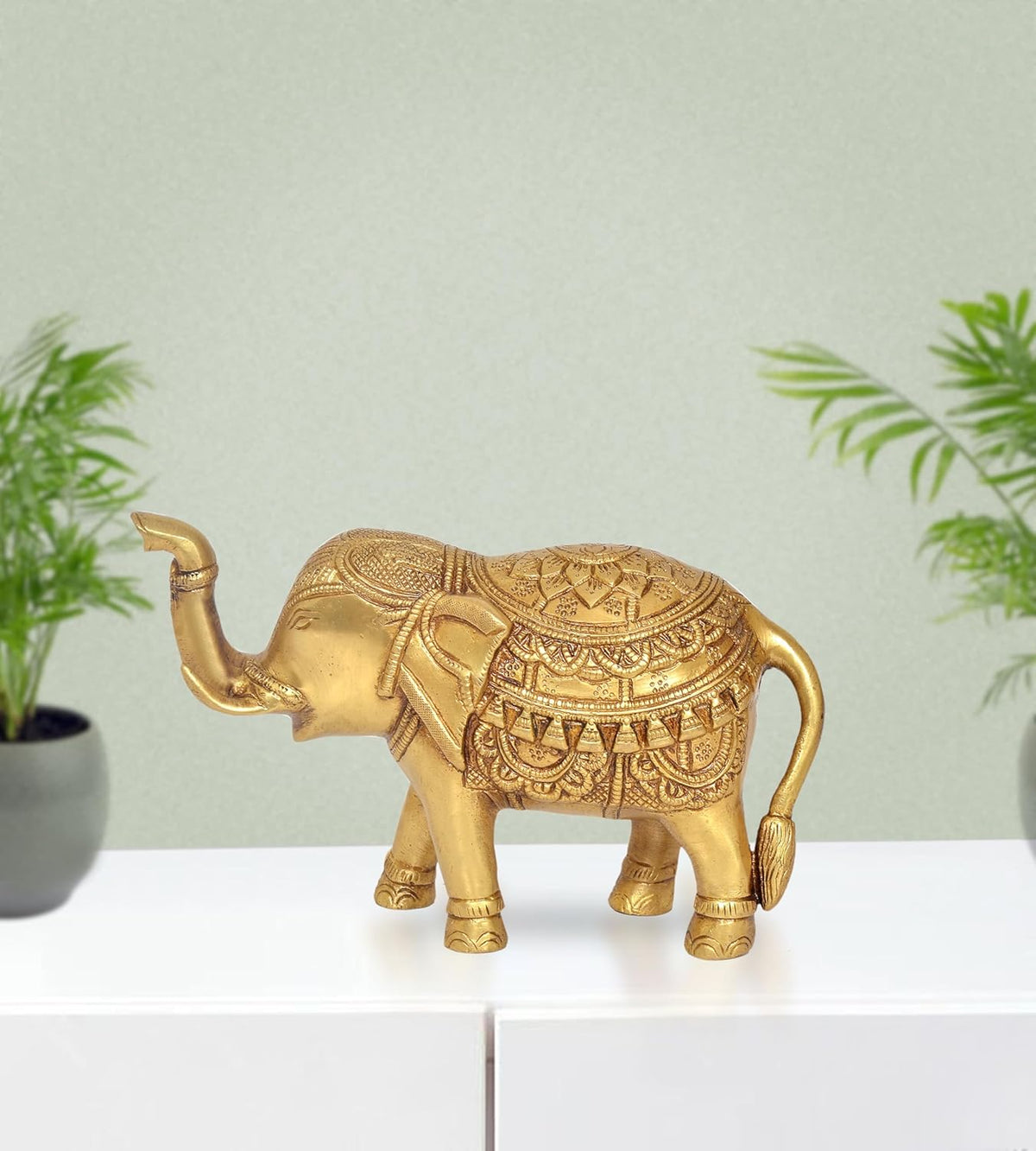 Gold brass elephant figurine with raised trunk and engraved detailed back.